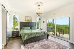 Spacious bedroom featuring wood-finish flooring, a decorative chandelier, and a barn door entry - 