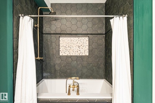 Bathtub with hexagonal dark tile surround, brass fixtures, and a recessed niche featuring speckled tile - 59102 Rge Road 234, Rural Westlock County, AB 