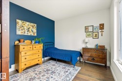 Bright room featuring wood-finish flooring, a vibrant accent wall, and white trim - 