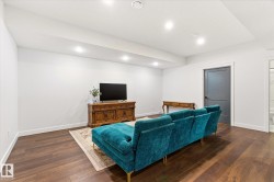 Open-concept living area featuring rich wood-finish flooring, white walls, and recessed lighting - 