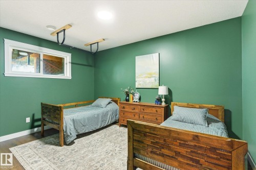 Bedroom featuring a window, wood-finish flooring, two wood bed frames, and a wood dresser - 59102 Rge Road 234, Rural Westlock County, AB 