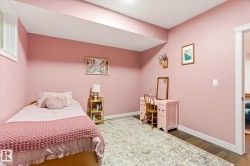 Versatile room featuring dark wood-finish flooring, light pink walls, white baseboards, and a white trim window - 
