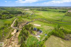 Expansive rural property featuring a main residence with a dark roof, a detached garage, and a smaller outbuilding - 