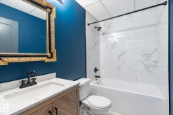 Bathroom featuring a wood-finish vanity with a white countertop and integrated sink, matte black faucet, and an ornate framed mirror - 