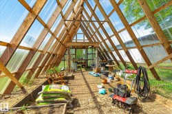 A-frame greenhouse structure featuring a clear panel roof and wood beam framing - 