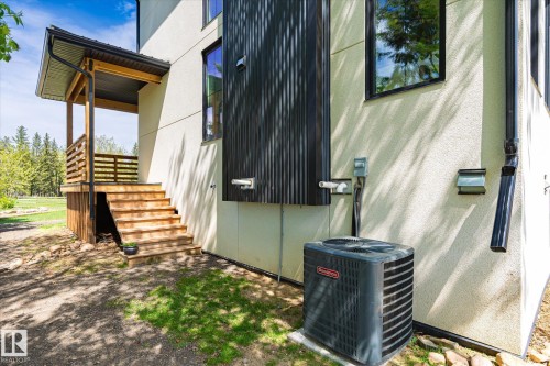 Exterior architectural details featuring a modern stucco finish, wood-tone porch with horizontal railings, and black corrugated siding accents - 59102 Rge Road 234, Rural Westlock County, AB 