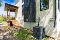 Exterior architectural details featuring a modern stucco finish, wood-tone porch with horizontal railings, and black corrugated siding accents - 
