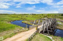Rural landscape featuring a wooden truss bridge spanning a dark water channel - 