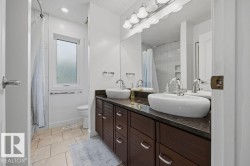 Renovated (2023) 5-pce main bath of the upper level featuring a large vanity with double sinks, marble tops and loads of storage. There is a lovely designer tile surround and ceramic tile flooring. - 