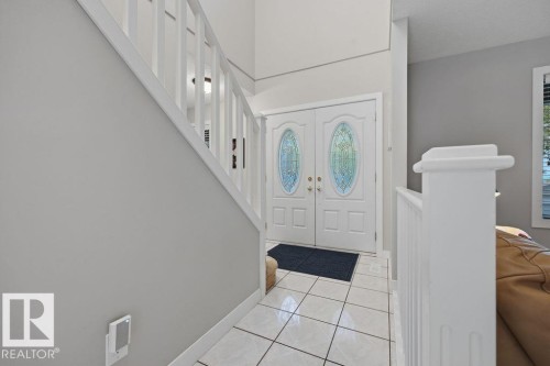Entryway featuring double doors with decorative glass inserts, ceramic tile flooring and a contemporary white staircase with matching balusters - 31 Wentworth Crescent, St. Albert, AB - Indoor Photo Showing Other Room