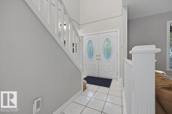 Entryway featuring double doors with decorative glass inserts, ceramic tile flooring and a contemporary white staircase with matching balusters - 