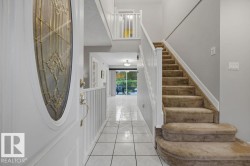 Entryway featuring a decorative glass door, tiled flooring and carpeted staircase - 