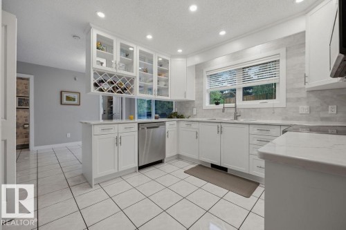 New kitchen (2025) featuring loads of ceiling height white cabinetry with glass-front uppers, quartz countertops, designer backsplash, a built-in wine rack, quality stainless steel appliances and lots of pot lights - 31 Wentworth Crescent, St. Albert, AB - Indoor Photo Showing Kitchen