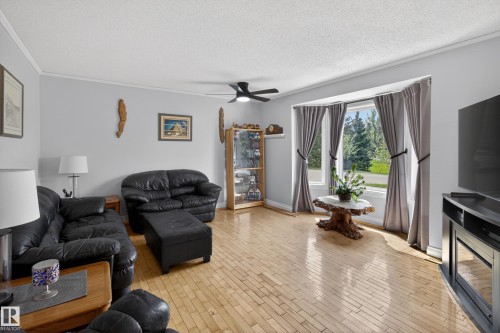 Bright living area featuring wood-finish flooring, a ceiling fan, and a large bay window - 110 52308 Rr 214, Rural Strathcona County, AB 