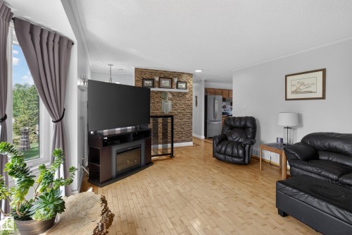Living area featuring wood-finish flooring, light grey painted walls, and a feature wall with stone veneer - 110 52308 Rr 214, Rural Strathcona County, AB 