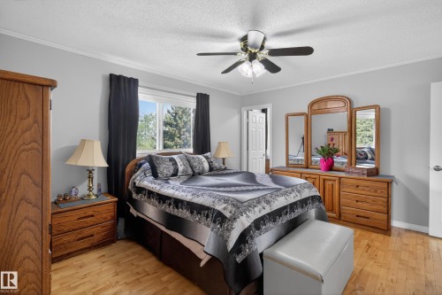 Bedroom with wood-finish flooring, a ceiling fan with light fixture, and a window providing natural light - 110 52308 Rr 214, Rural Strathcona County, AB 