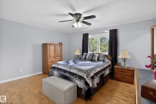 Spacious room with wood-finish flooring, a ceiling fan, and a large window offering natural light - 110 52308 Rr 214, Rural Strathcona County, AB 