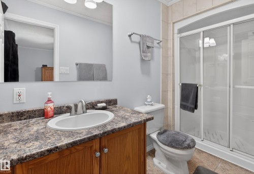 Bathroom featuring a wood vanity with a speckled countertop and an integrated sink - 110 52308 Rr 214, Rural Strathcona County, AB 