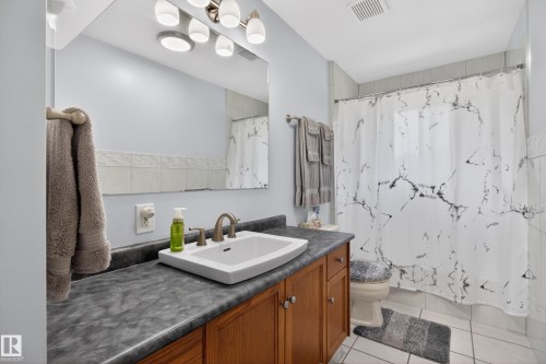 Bathroom vanity featuring a vessel sink, brushed nickel faucet, and wood-finish cabinetry with silver hardware - 110 52308 Rr 214, Rural Strathcona County, AB 