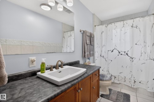 Bathroom vanity featuring a rectangular undermount sink, brushed nickel faucet, and wood-finish cabinetry with silver-tone hardware - 110 52308 Rr 214, Rural Strathcona County, AB 