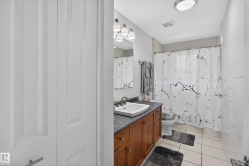 Bathroom featuring a wood-finish vanity with an integrated sink, a dark countertop, and brass-tone hardware - 110 52308 Rr 214, Rural Strathcona County, AB 