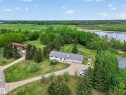 Ranch-style residence featuring a prominent metal roof, attached two-car garage, and a gravel driveway - 110 52308 Rr 214, Rural Strathcona County, AB 