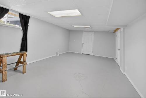 Spacious room featuring light gray walls, a dropped ceiling with recessed lighting, and a window with dark drapes - 110 52308 Rr 214, Rural Strathcona County, AB 