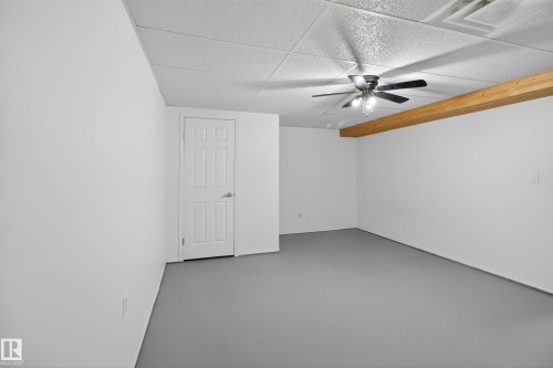 Spacious room featuring white painted walls, a drop ceiling, and grey flooring - 110 52308 Rr 214, Rural Strathcona County, AB 