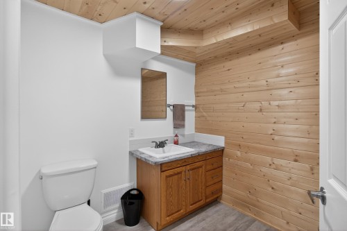 Bathroom featuring a single vanity with wood cabinetry, a granite-finish countertop, and a rectangular sink - 110 52308 Rr 214, Rural Strathcona County, AB 