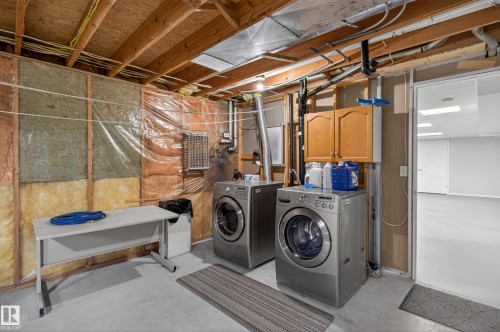 Utility area featuring a concrete floor, exposed wood ceiling joists, and a built-in wood cabinet - 110 52308 Rr 214, Rural Strathcona County, AB 