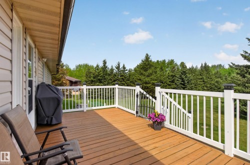 Expansive rear deck featuring wood-finish decking, white railings with black post caps, and a gate - 110 52308 Rr 214, Rural Strathcona County, AB 