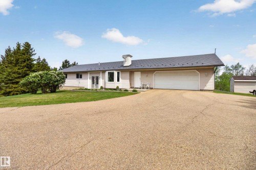 Ranch-style residence featuring a dark metal roof, light-toned siding, and an attached two-car garage - 110 52308 Rr 214, Rural Strathcona County, AB 