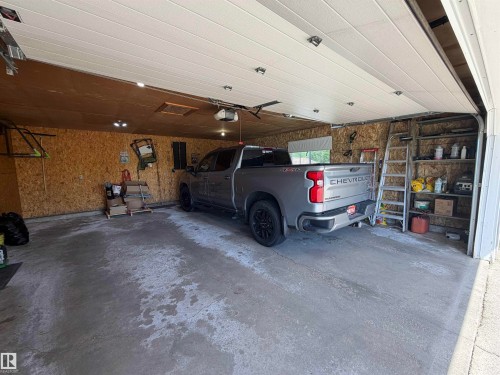 Spacious attached garage featuring a concrete floor, built-in shelving, and a paneled garage door - 110 52308 Rr 214, Rural Strathcona County, AB 