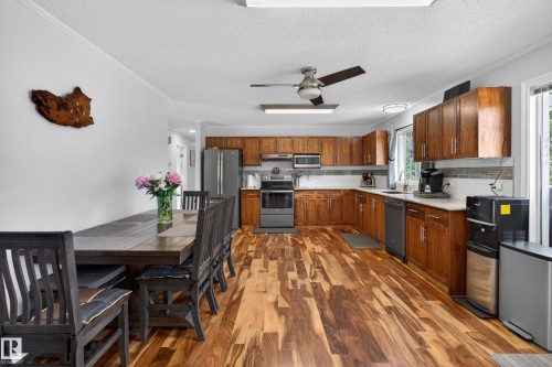 Open-concept kitchen and dining area featuring wood-finish flooring, wood cabinetry, light countertops, and a tile backsplash - 110 52308 Rr 214, Rural Strathcona County, AB 