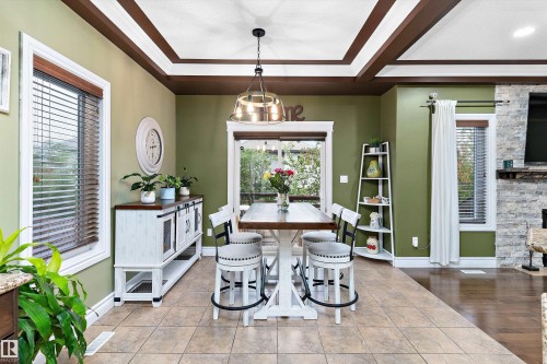 Open concept dining space featuring a coffered ceiling with dark wood accents, tiled flooring, and multiple windows with wood blinds - 16609 58A Street, Edmonton, AB 