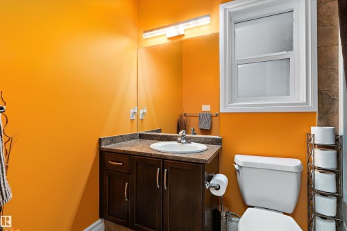 Powder room featuring a dark wood-finish vanity with an integrated sink and a speckled countertop - 16609 58A Street, Edmonton, AB 