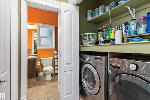 Dedicated laundry closet with built-in shelving, complemented by an adjacent bathroom featuring a window, brown vanity with a light-colored countertop, and a toilet - 16609 58A Street, Edmonton, AB 