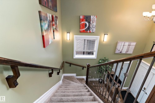 Carpeted staircase featuring a wood-finish handrail and metal balusters - 16609 58A Street, Edmonton, AB 