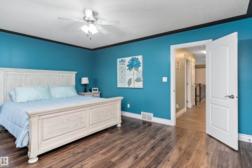 Spacious room featuring wood-finish flooring, a ceiling fan with light fixture, and white baseboards - 16609 58A Street, Edmonton, AB 