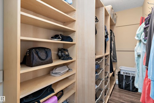 Custom closet system featuring light wood-finish shelving, integrated hanging rods, and pull-out wire baskets - 16609 58A Street, Edmonton, AB 