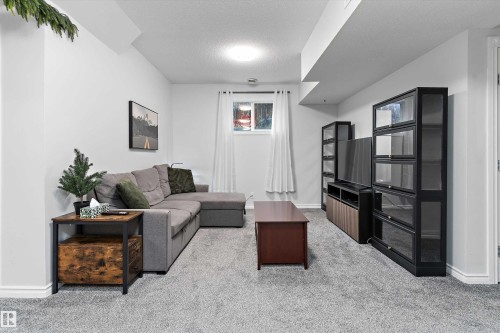 Finished lower level featuring light gray carpeting, recessed lighting, white walls, and a window with white drapes - 16609 58A Street, Edmonton, AB 