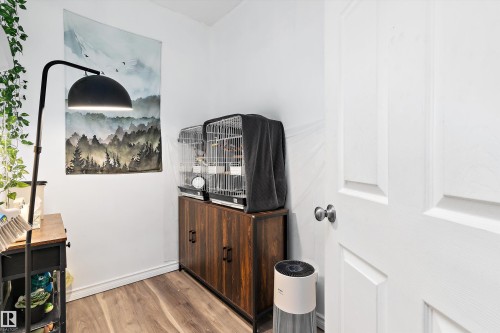 Compact interior space featuring wood-finish flooring, white baseboards, and a paneled white door - 16609 58A Street, Edmonton, AB 