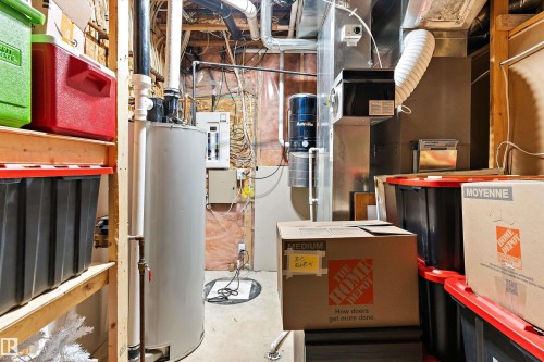 Utility room featuring a water heater, furnace system, water filtration unit, exposed insulation, and concrete flooring - 16609 58A Street, Edmonton, AB 