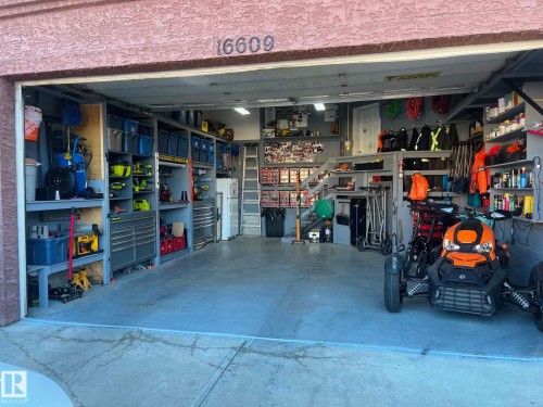 Spacious garage featuring extensive built-in shelving, organized storage solutions, a durable concrete floor, and overhead lighting - 16609 58A Street, Edmonton, AB 