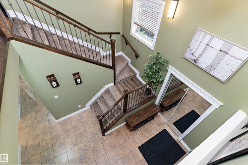 Two-story staircase featuring dark wood handrails and wrought iron balusters - 16609 58A Street, Edmonton, AB 