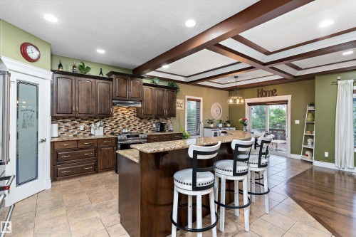 Kitchen featuring dark wood cabinetry, a tiled backsplash, and granite countertops - 16609 58A Street, Edmonton, AB 