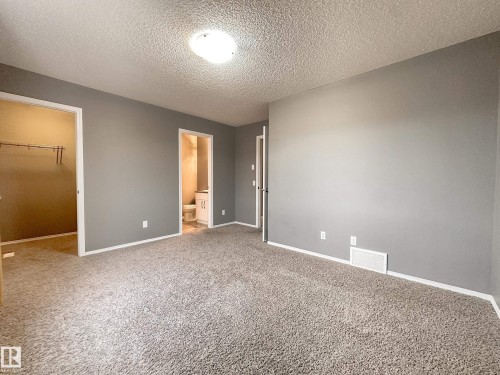Spacious room featuring neutral gray walls, plush carpeting, and white baseboards - 9432 211 Street, Edmonton, AB 