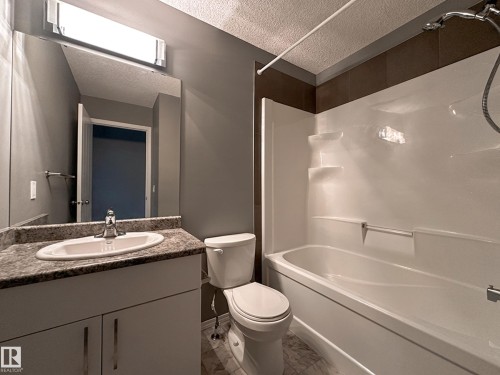 Bathroom featuring a white vanity with a speckled countertop, undermount sink, and chrome faucet - 9432 211 Street, Edmonton, AB 
