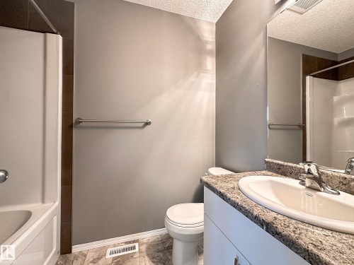 Bathroom featuring a white bathtub, toilet, and vanity with an integrated sink - 9432 211 Street, Edmonton, AB 