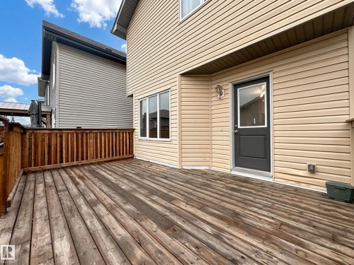 Expansive wood-finish deck with a wood railing and direct access to the interior via a dark-paneled door with an upper glass insert - 9432 211 Street, Edmonton, AB 